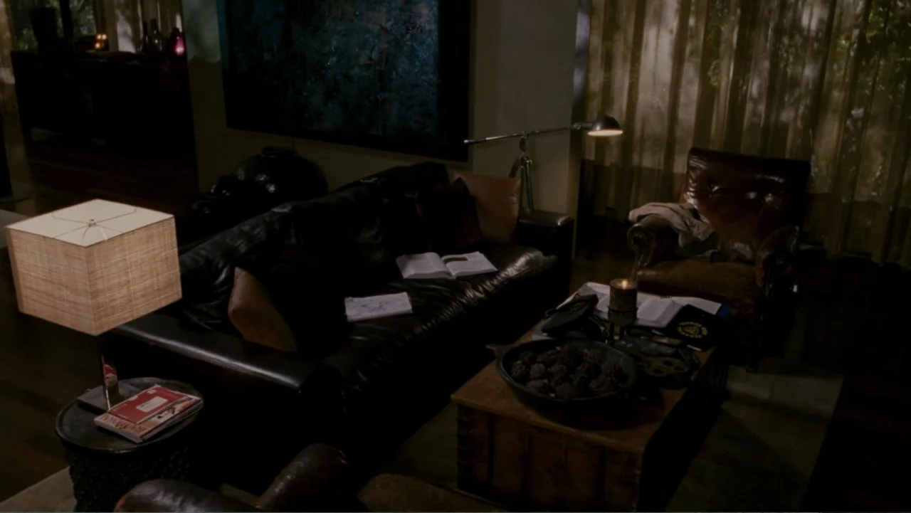 When a Stranger Calls (2006) movie still: medium — A dimly lit living room features a leather sofa and armchair. Various books, a lit candle, and…