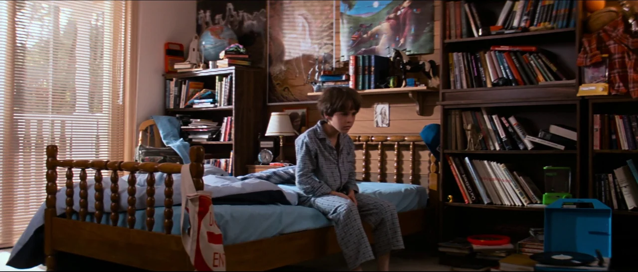 The NeverEnding Story (1984) movie still: fullbody — A cluttered child's bedroom features wooden furniture, tall bookshelves, and a window with…