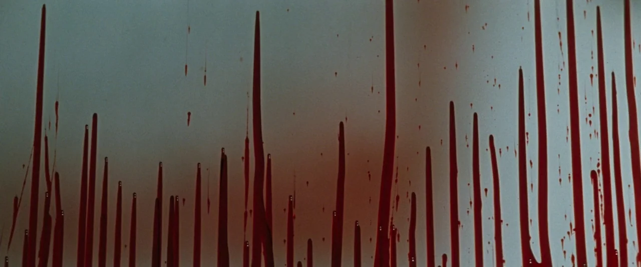In The Mouth of Madness (1994) movie still: closeup — A flat, neutral-toned wall is covered in multiple long, vertical streaks of red fluid. The…