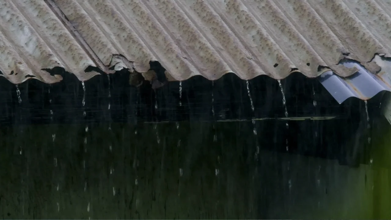 Torn Apart: Separated at the Border (2019) movie still: closeup — A rusted corrugated metal roof overhangs a dark shadowed vertical surface.…