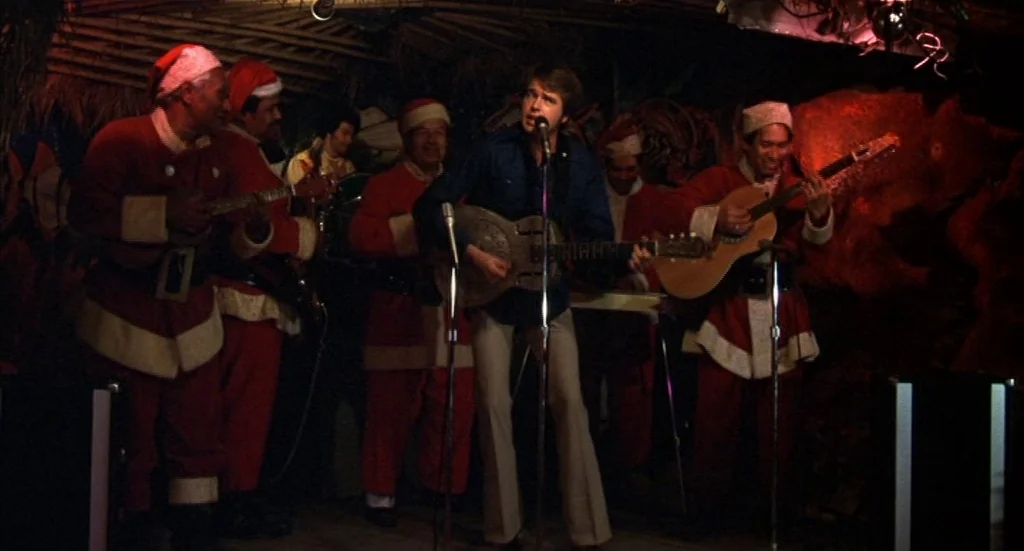 Melvin & Howard (1980) movie still: medium — A dimly lit lounge featuring musicians dressed in Santa Claus costumes performing on stage. Red…