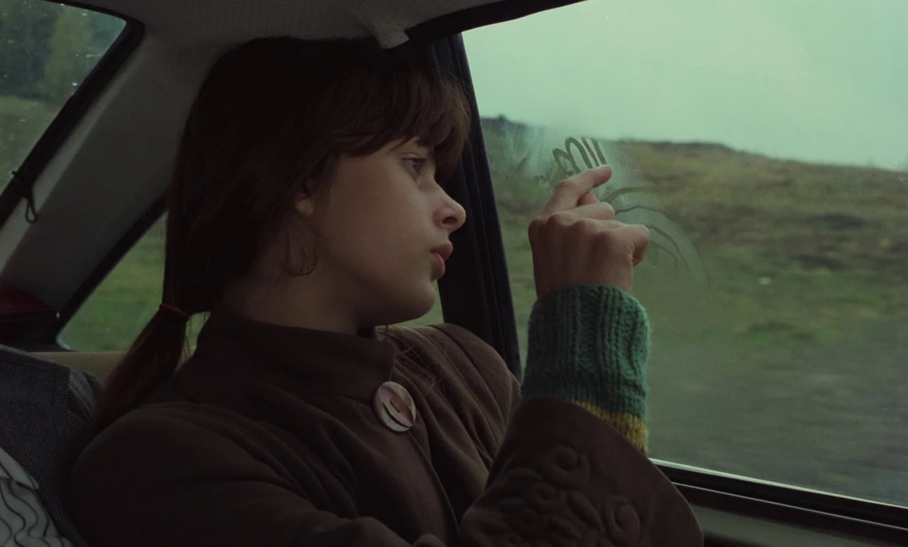 Wrong Move (1975) movie still: medium — A teenager sits in the backseat of a moving vehicle looking out the window. She uses her finger to trace…