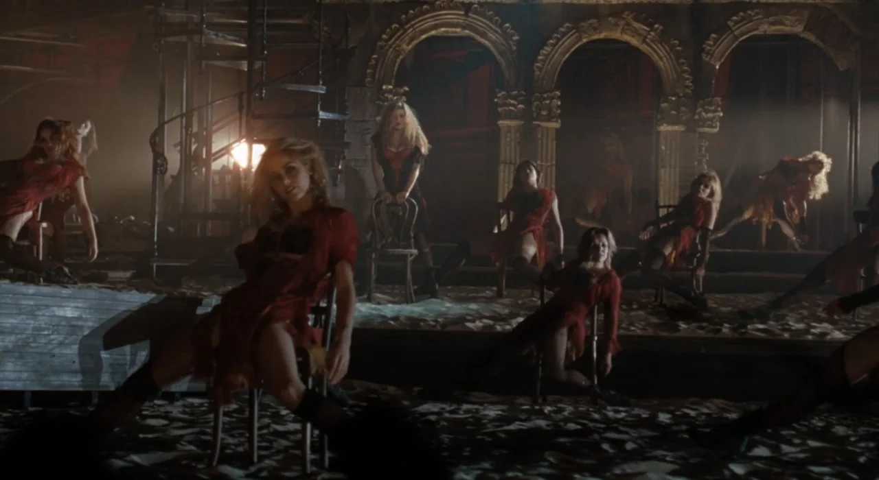 The Great Beauty (2013) movie still: fullbody — An interior stage floor covered in sand features several stone archways in the back. Multiple women…