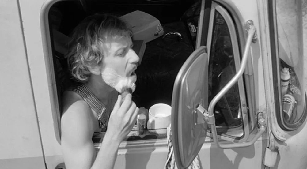 Kings of the Road (Im Lauf der Zeit) (1976) movie still: medium — The interior of a cramped truck cab is used as a makeshift bathroom. A man leans…