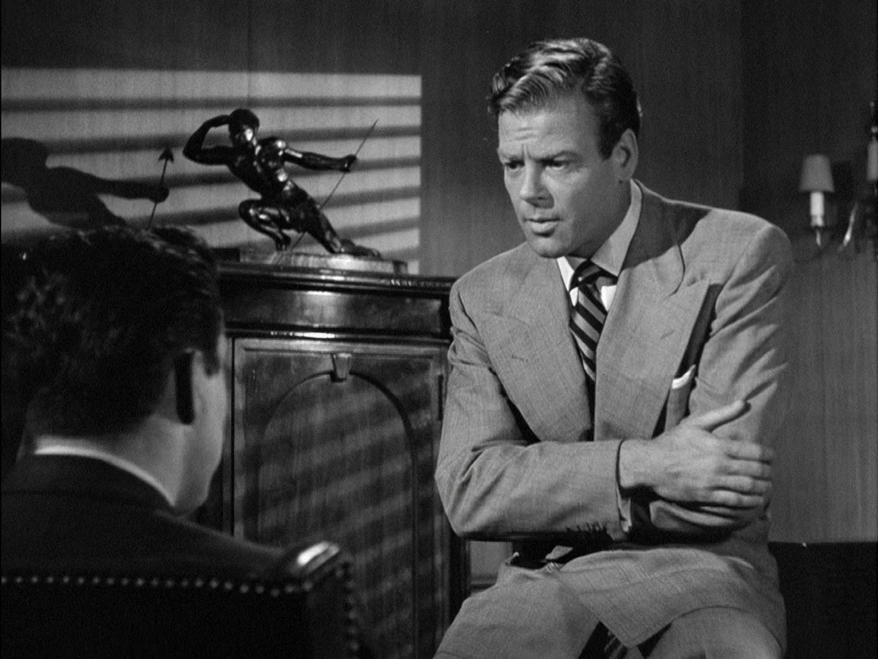 D.O.A. (1949) movie still: medium — An interior office space featuring wood-paneled walls and a venetian blind light pattern. A man in a suit…