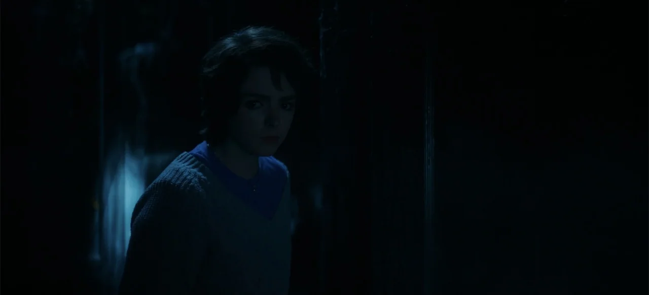 My Best Friend's Exorcism (2022) movie still: medium — A dimly lit interior space is shrouded in deep shadows and cool blue light. A young woman…