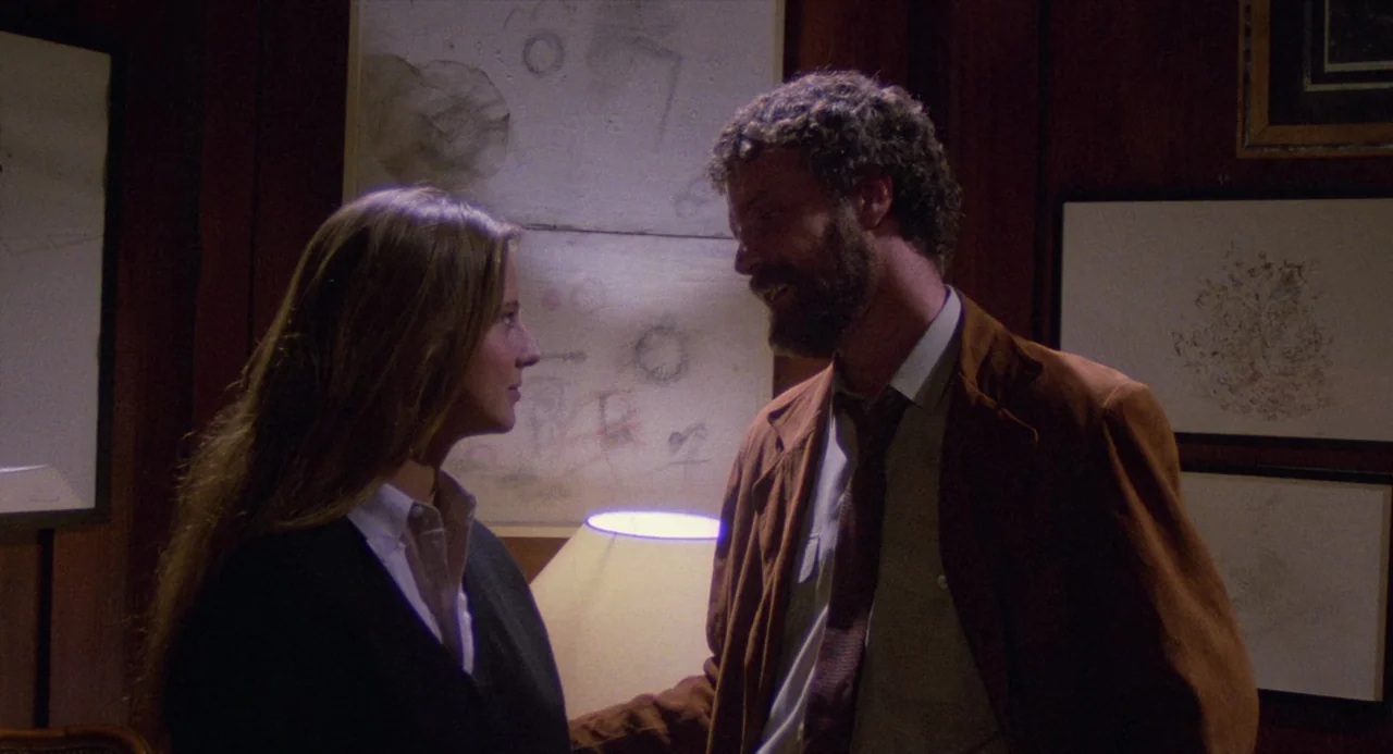 City of the Living Dead (1980) movie still: medium — A dimly lit room features wood-paneled walls decorated with several framed drawings. A man with…