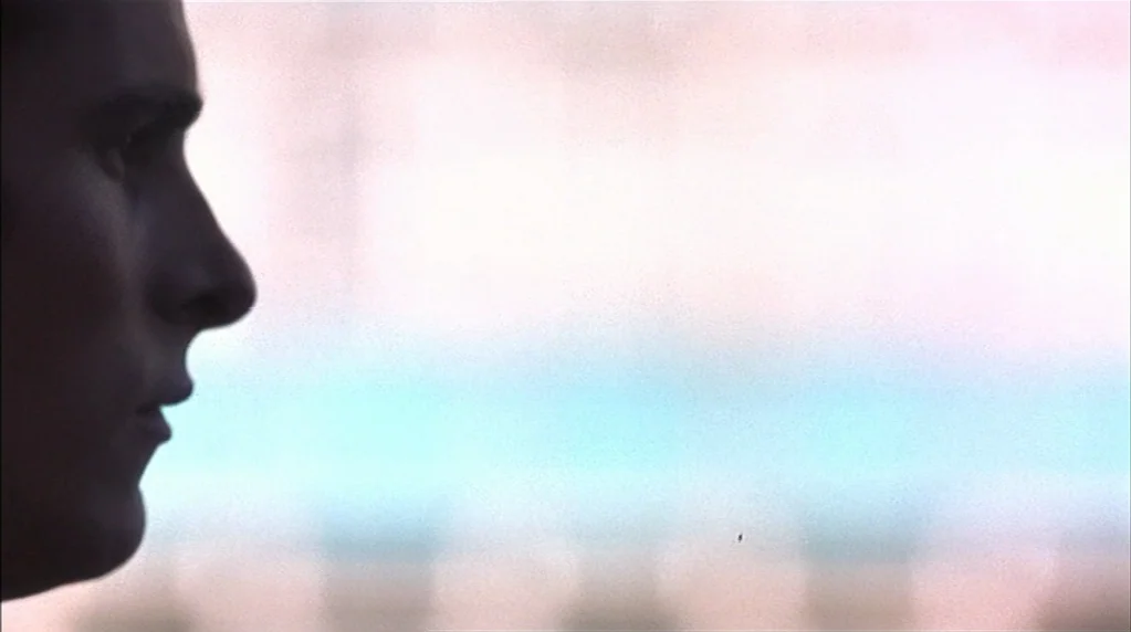Velvet Goldmine (1998) movie still: closeup — A close-up shot focuses on the dark silhouette of a person's face. The subject is seen in profile…
