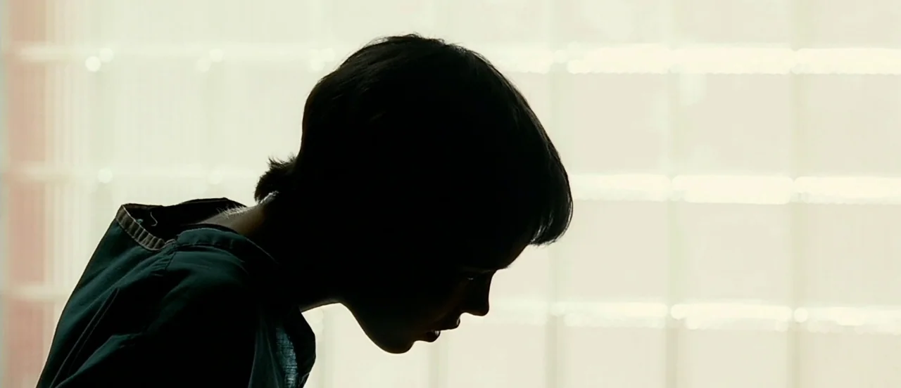 Hard Candy (2005) movie still: closeup — A dark silhouette of a young person's head and shoulders against a bright background. The subject leans…
