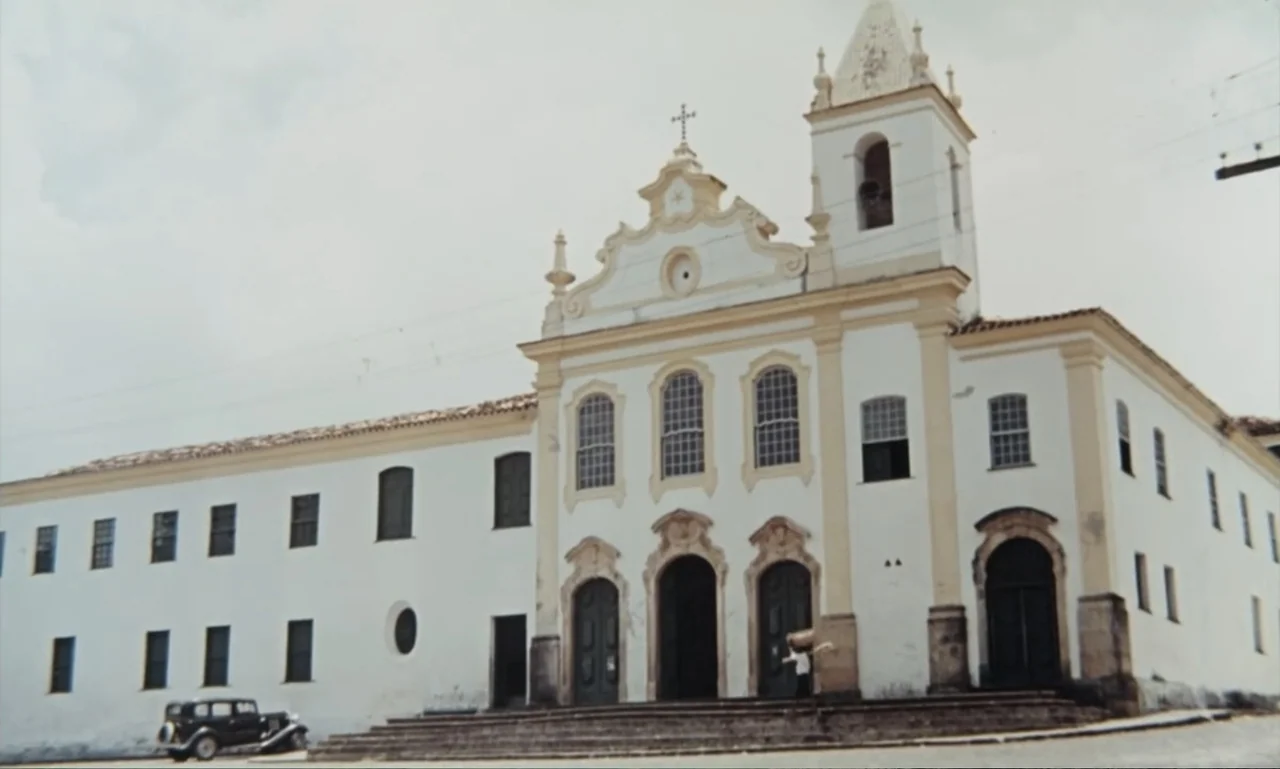 Dona Flor and Her Two Husbands (1976) movie still: establishing — A white colonial-style stone church features a bell tower and arched entrances. A…