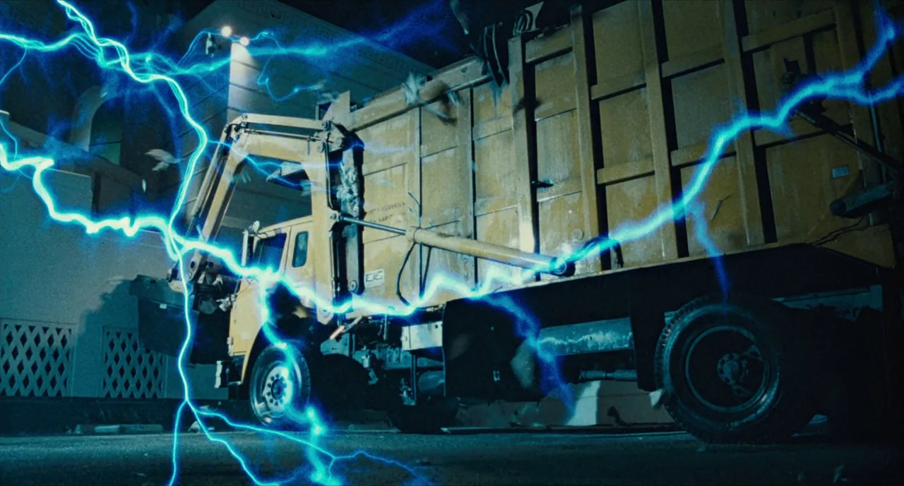 The Terminator (1984) movie still: wide — An industrial-looking yellow sanitation truck is parked in a dark alley at night. A bright blue electrical…