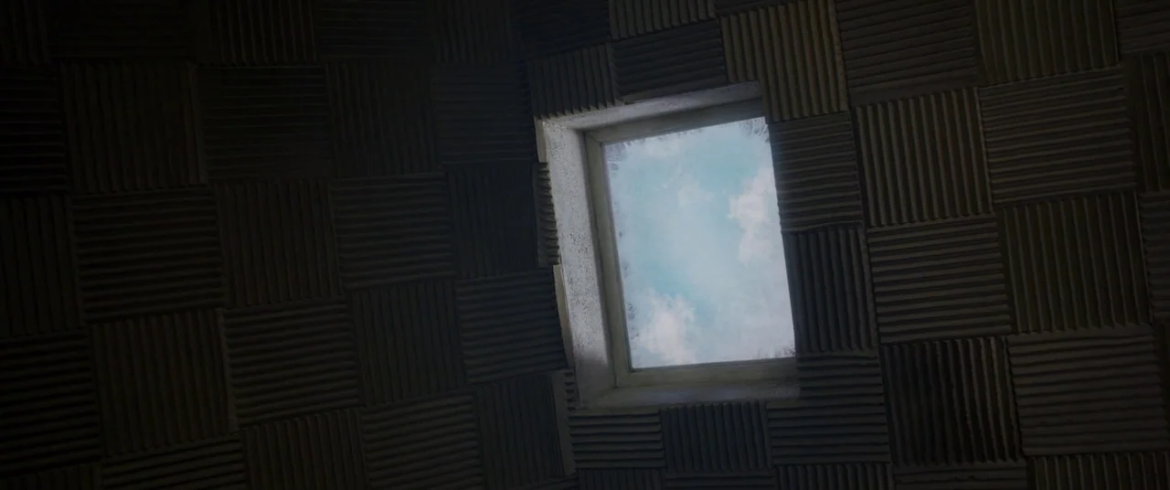 Room (2015) movie still: establishing — A square ceiling window looks out onto a light blue, cloudy sky. The surrounding ceiling is covered in dark,…