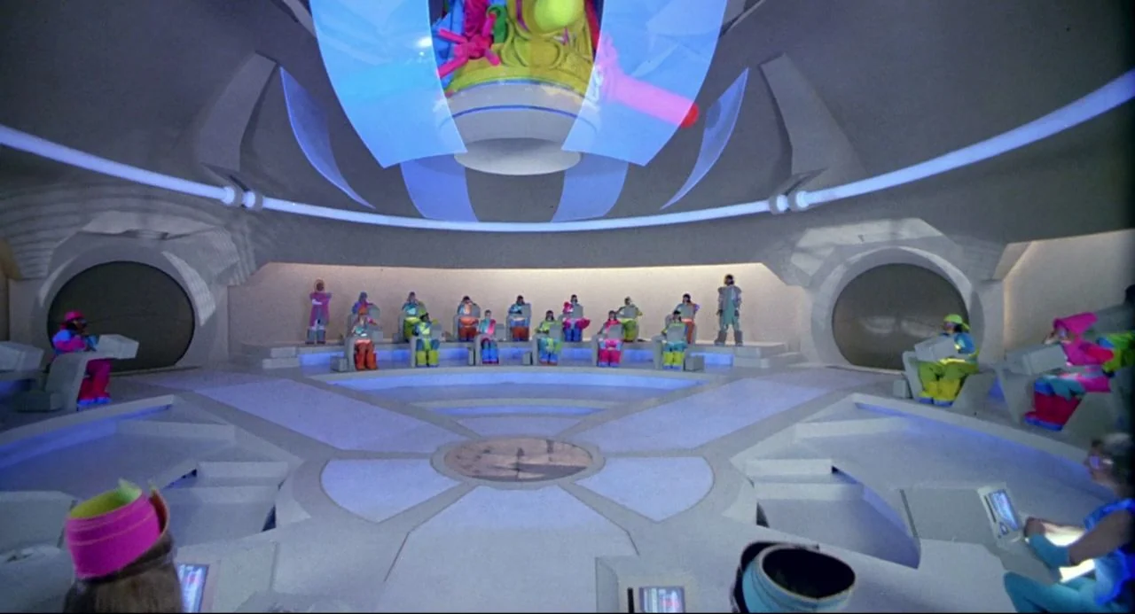 Bill and Ted’s Bogus Journey (1991) movie still: wide — A spacious, minimalist circular room features white geometric consoles arranged in radial…