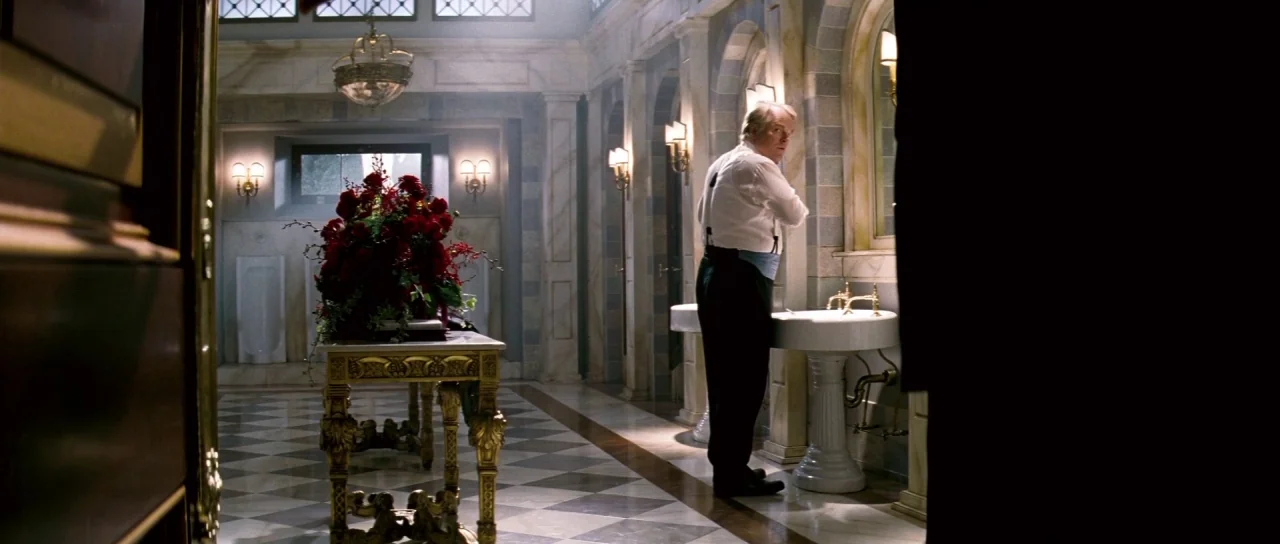Down With Love (2003) movie still: wide — An ornate tiled restroom features white marble walls and a large bouquet of flowers. A man stands before a…