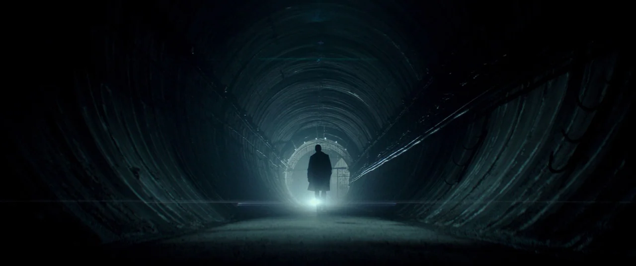 Atomic Blonde (2017) movie still: wide — A long, circular concrete tunnel stretches into the distance with rows of mounted pipes. A solitary figure…