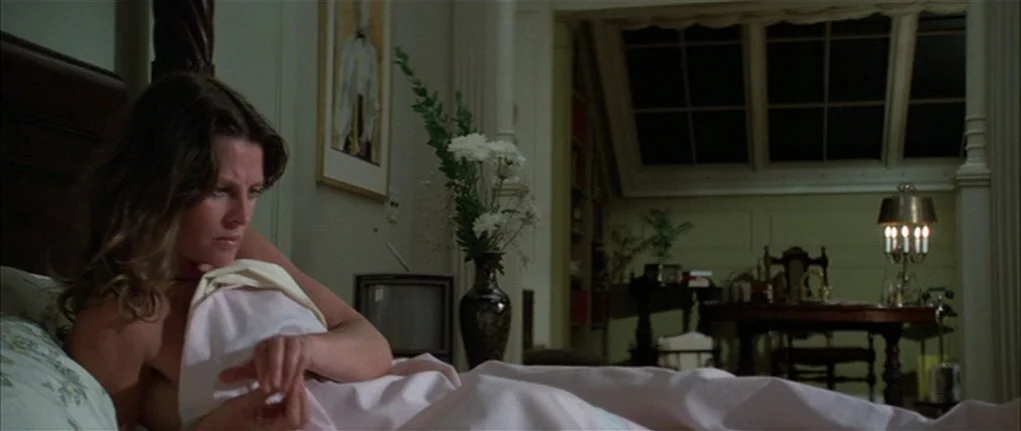 Demon Seed (1977) movie still: medium — A quiet bedroom with dark wooden furniture and a large window at night. A woman rests in bed while…