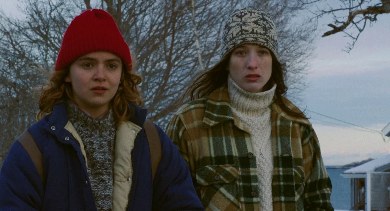 Blow The Man Down (2019) movie still: medium — A snowy coastline during twilight with bare trees visible against a dim sky. Two women dressed in…