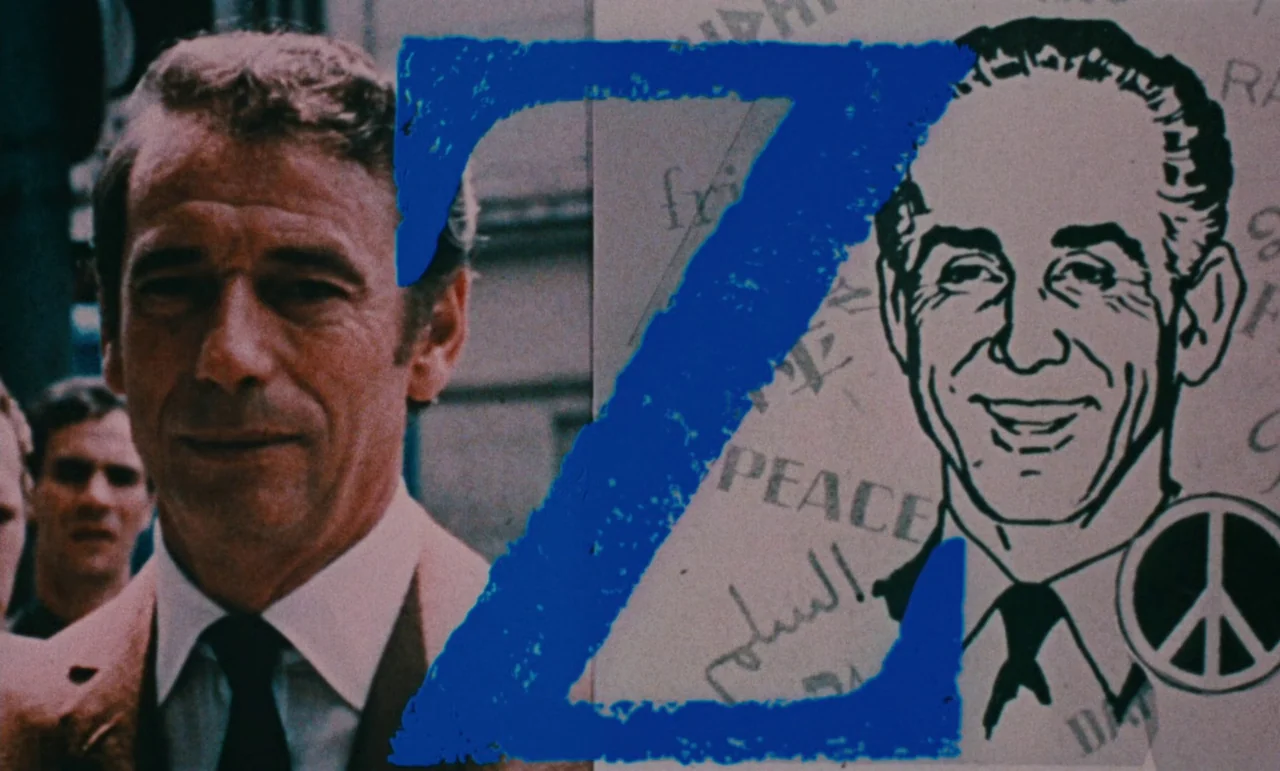 Z (1969) movie still: closeup — An outdoor urban environment features a man partially obscured by a graphic overlay. A large blue letter Z is…