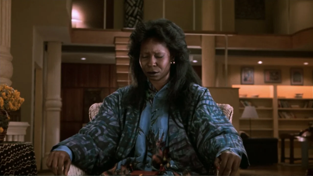 Ghost (1990) movie still: medium — A spacious 1990s style living room features a mezzanine level and built-in wooden bookshelves. A woman sits in a…