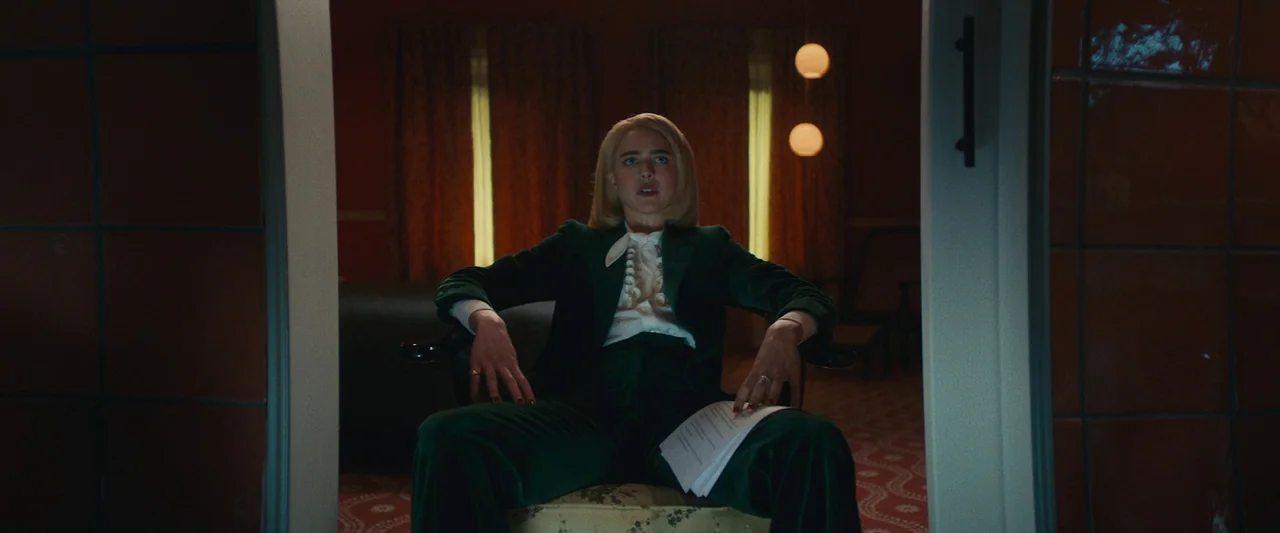 Sanctuary (2023) movie still: medium — A dimly lit room features patterned carpeting and curtains illuminated by warm spherical wall lamps. A woman…