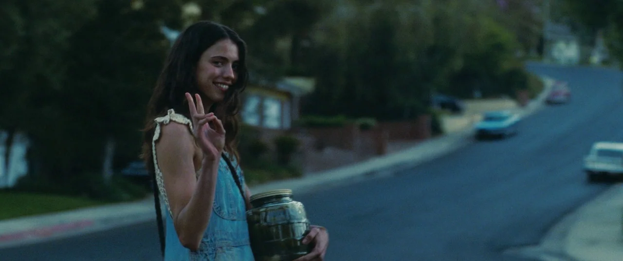 Once Upon a Time… In Hollywood (2019) movie still: medium — A suburban street at dusk with parked cars and blurred houses in the background. A young…