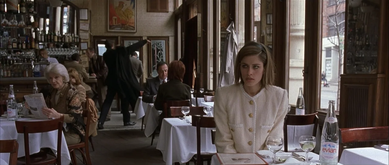 Igby Goes Down (2002) movie still: medium — A classic bistro features white-clothed tables, dark wooden window frames, and glass bottles. A young…