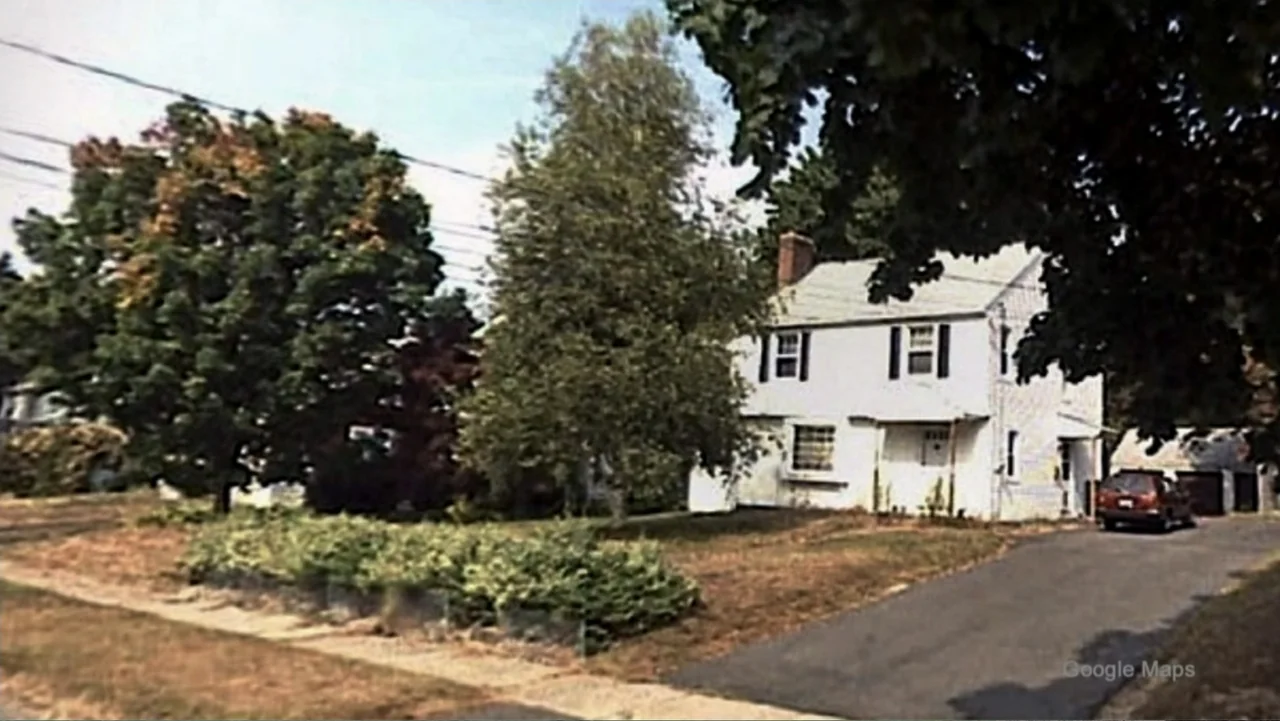 Requiem for the Dead: American Spring 2014 (2015) movie still: establishing — A white two-story suburban house sits on a lot with green trees and…