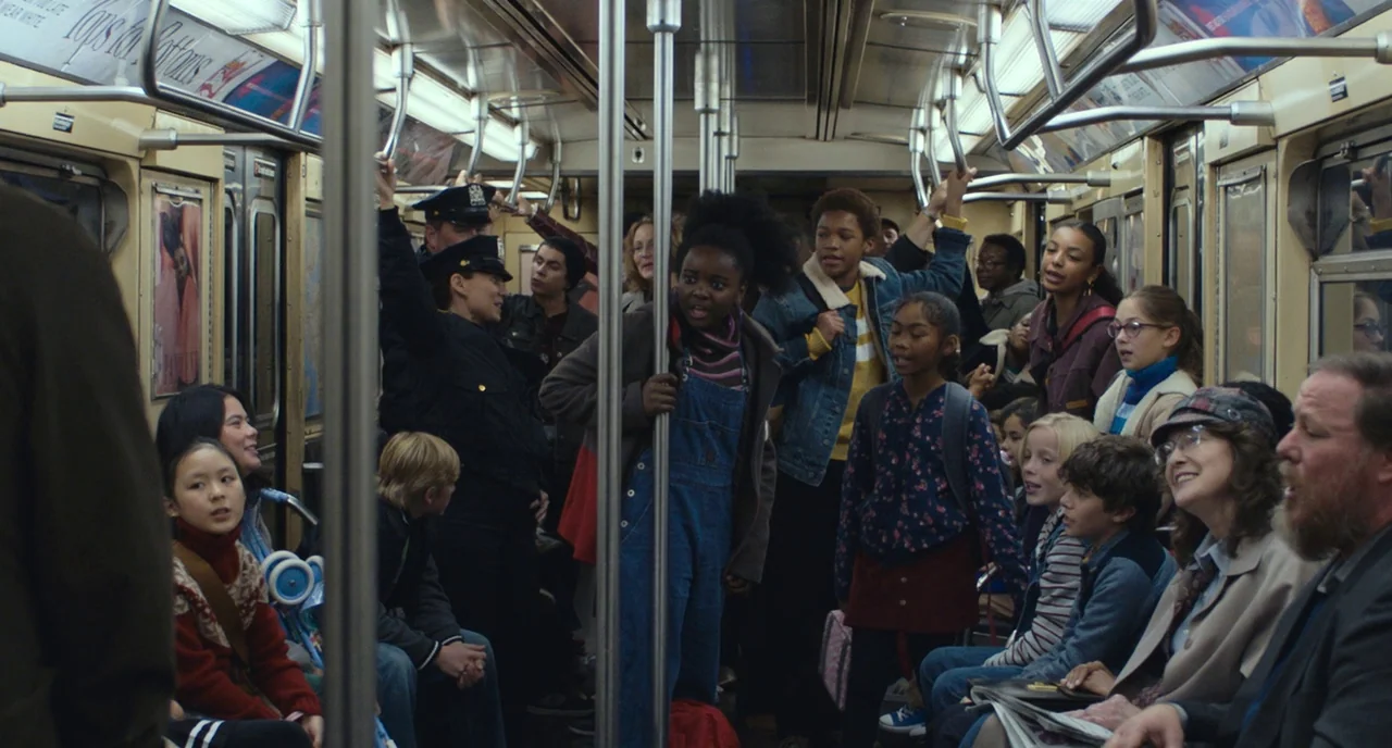 A Beautiful Day In The Neighborhood movie still: wide — A crowded New York City subway car during a daytime transit commute. Diverse passengers of…