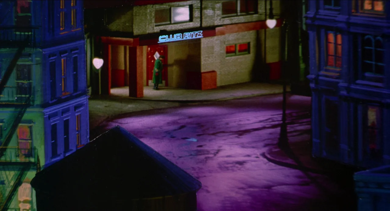 Dick Tracy (1990) movie still: establishing — A miniature urban street intersection at night features a building labeled Club Ritz. A single figure…