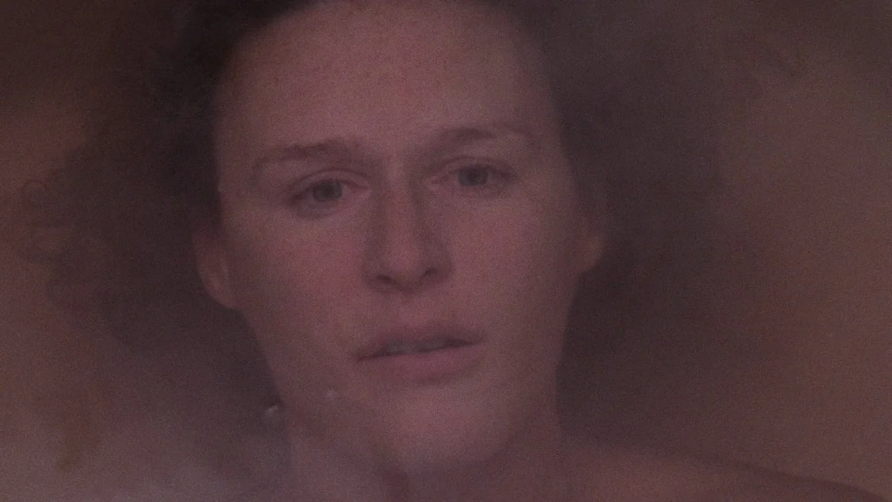 Fatal Attraction (1987) movie still: closeup — A dark, enclosed space containing water and a human face. The subject rests partially submerged in…