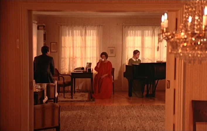 Autumn Sonata (1978) movie still: wide — A spacious room features a piano, tea table, and chairs near thin white curtains. A man sits in a chair, a…