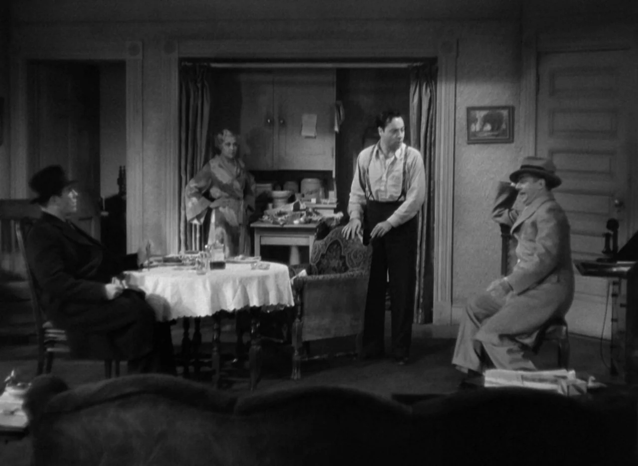 The Thin Man (1934) movie still: wide — A furnished apartment interior contains a table, chairs, cabinets, and a framed wall picture. Four adults…