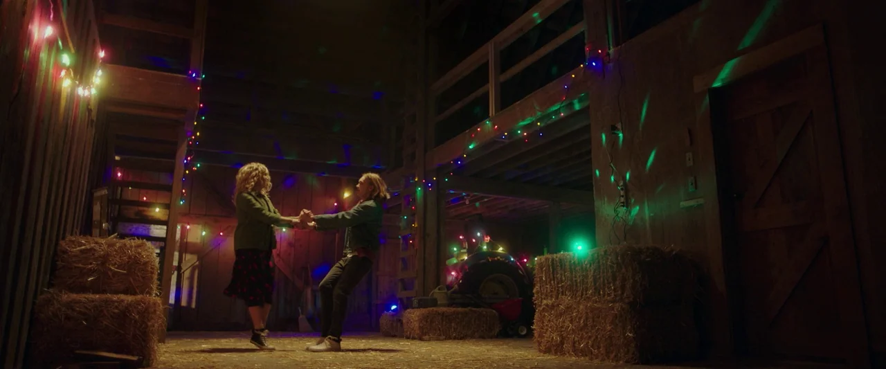 Spontaneous (2020) movie still: fullbody — A spacious barn interior with wooden beams and stacked hay bales. A young man and woman are holding hands…