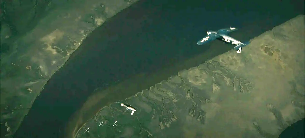 Devotion (2022) movie still: establishing — A dark river winds through vast stretches of marshy land and mud flats. A lone propeller plane with navy…