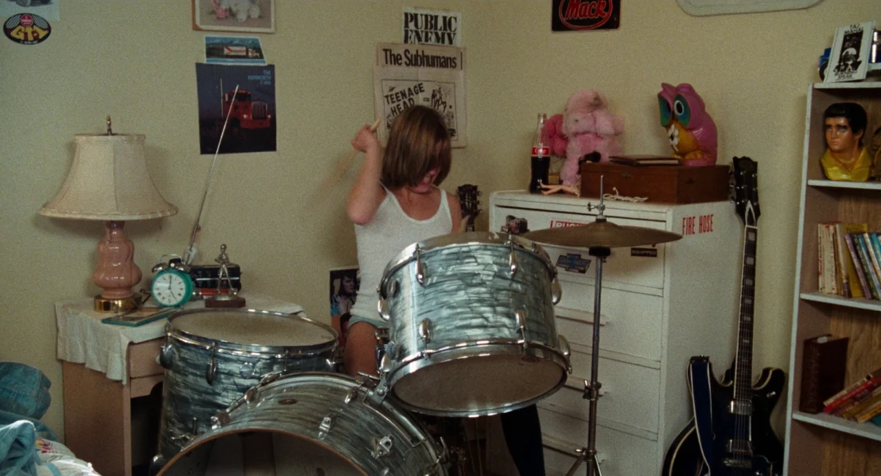 Out of the Blue (1980) movie still: medium — A teenager's room is filled with music posters, instruments, and varied trinkets. A young person in a…