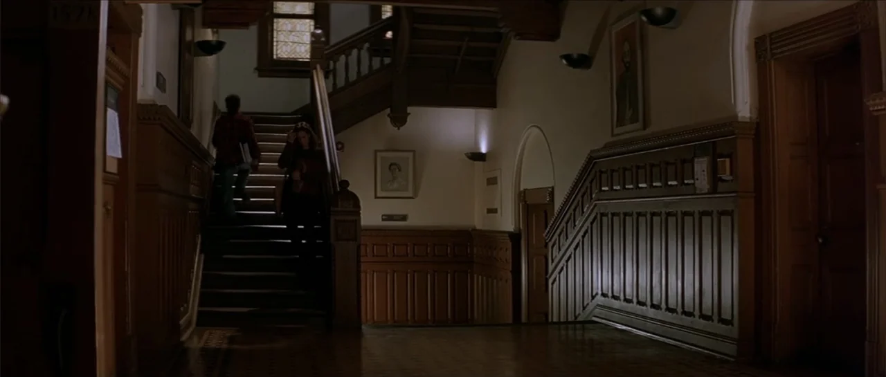 Moonlight and Valentino (1995) movie still: wide — An interior wooden staircase in a historic building with paneled walls and wall lamps. Two…