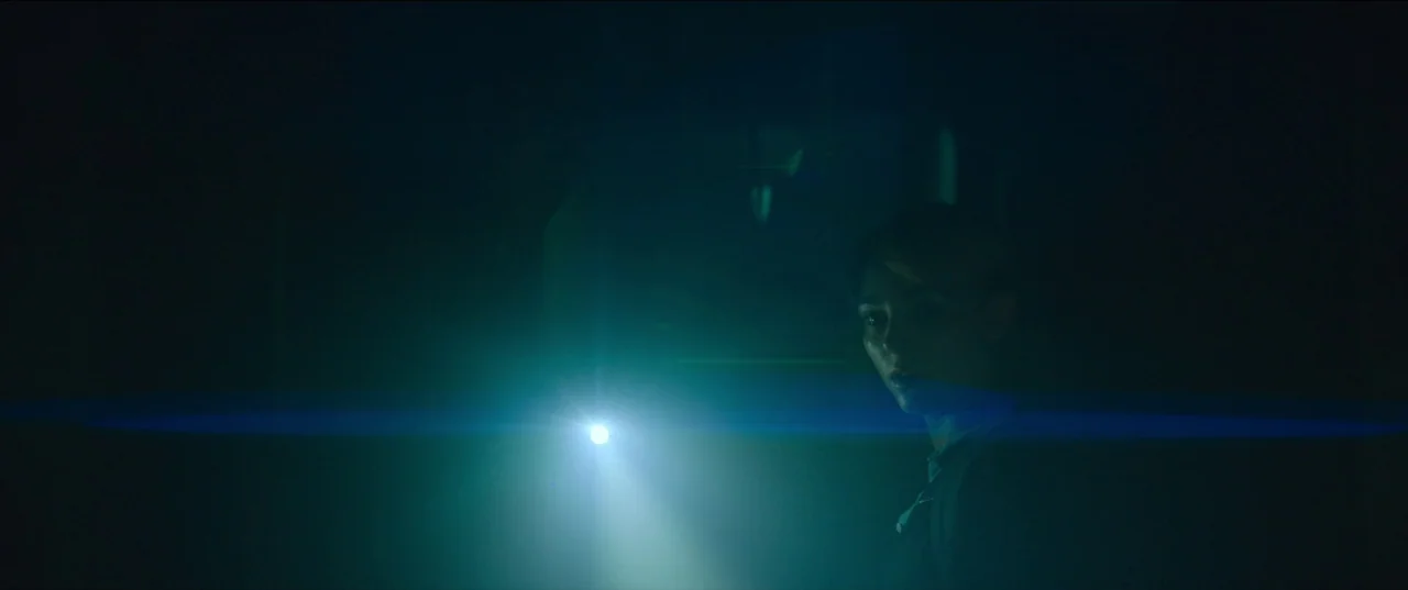 Rebel Ridge (2024) movie still: medium — A dark space is partially illuminated by a bright beam of artificial light. A woman holds a flashlight…