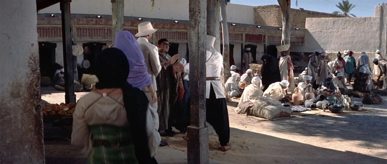 Legend of the Lost (1957) movie still: medium — A bustling North African market features sandy ground and numerous vendor stalls under awnings.…