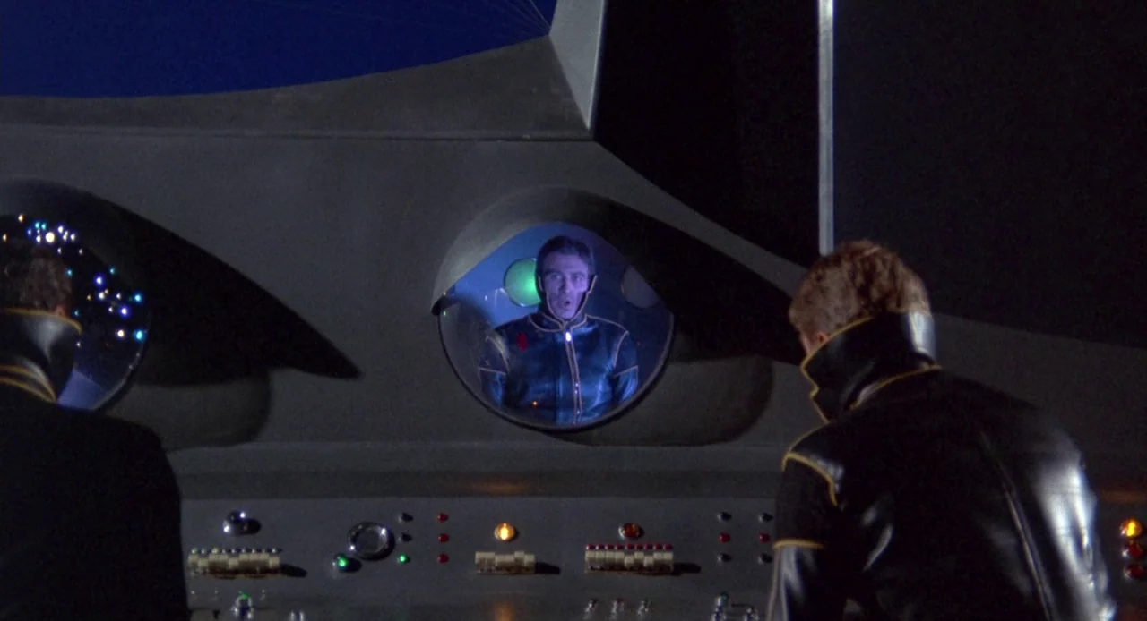 Planet of the Vampires (1965) movie still: medium — A dark spaceship cockpit features a control console with illuminated buttons and small…