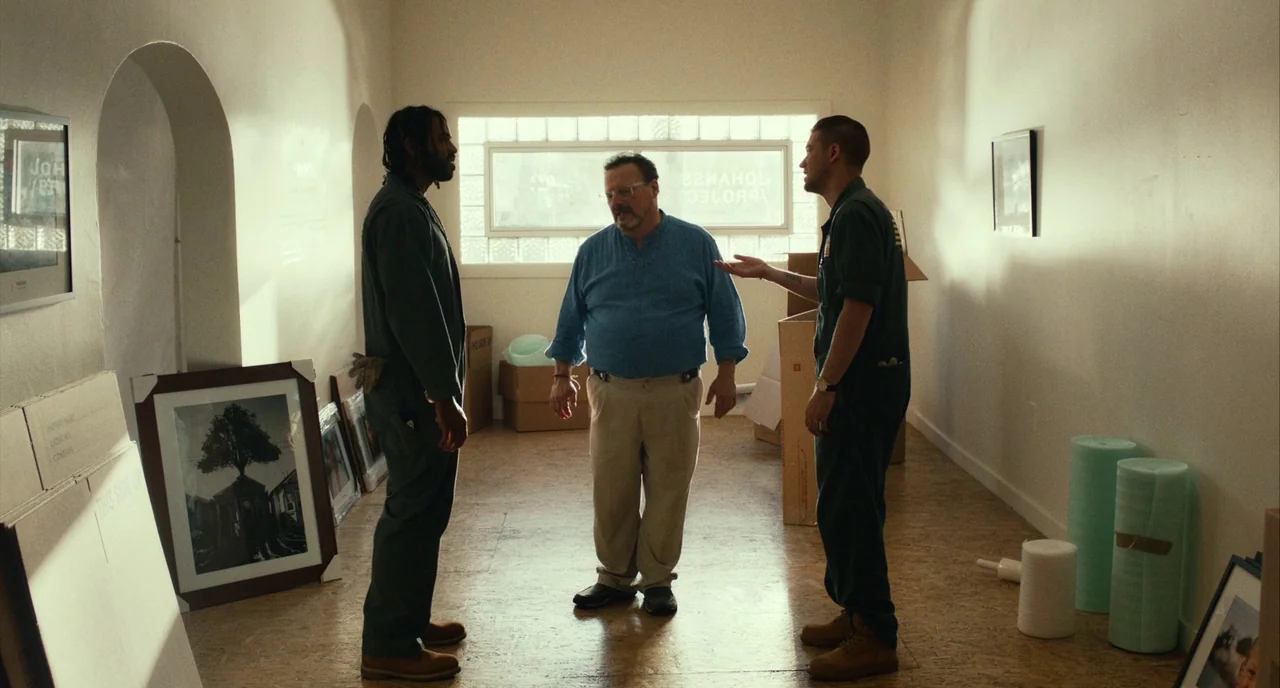 Blindspotting (2018) movie still: fullbody — An interior space filled with packed art pieces, cardboard boxes, and protective foam rolls. Three men…