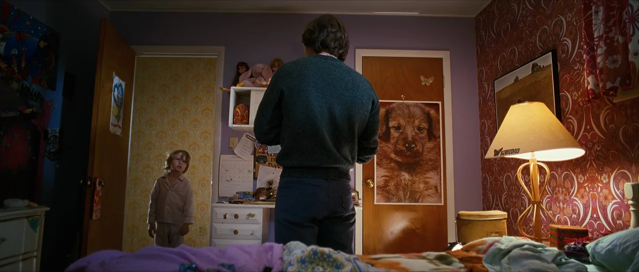 The Lovely Bones (2009) movie still: medium — A dimly lit room features purple walls covered in 1970s style patterned floral wallpaper. A man stands…