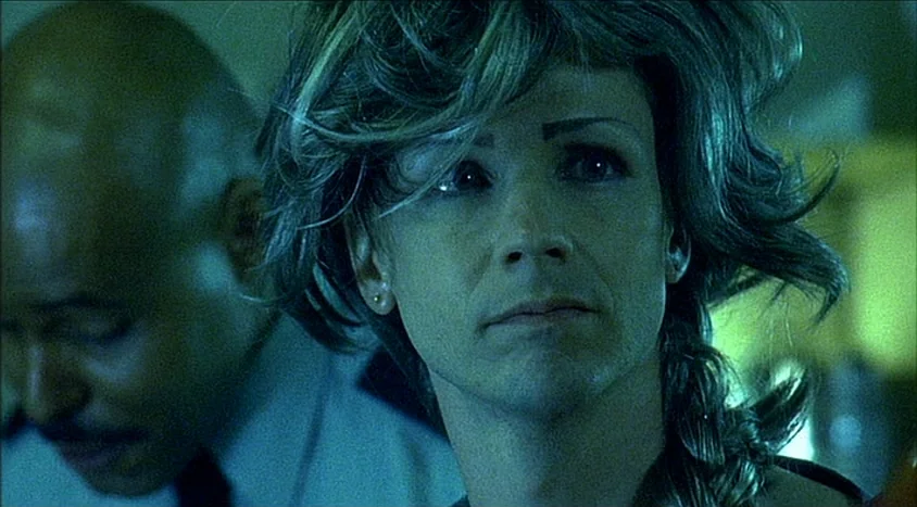 Hedwig and the Angry Inch (2001) movie still: closeup — An office environment with dim, greenish lighting casts shadows across the subjects' faces.…