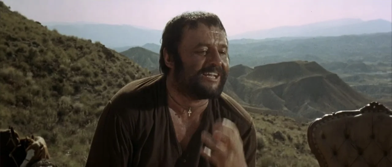 Duck, You Sucker (1971) movie still: medium — A man stands outdoors in a hilly, arid desert environment under bright daylight. The man in a brown…