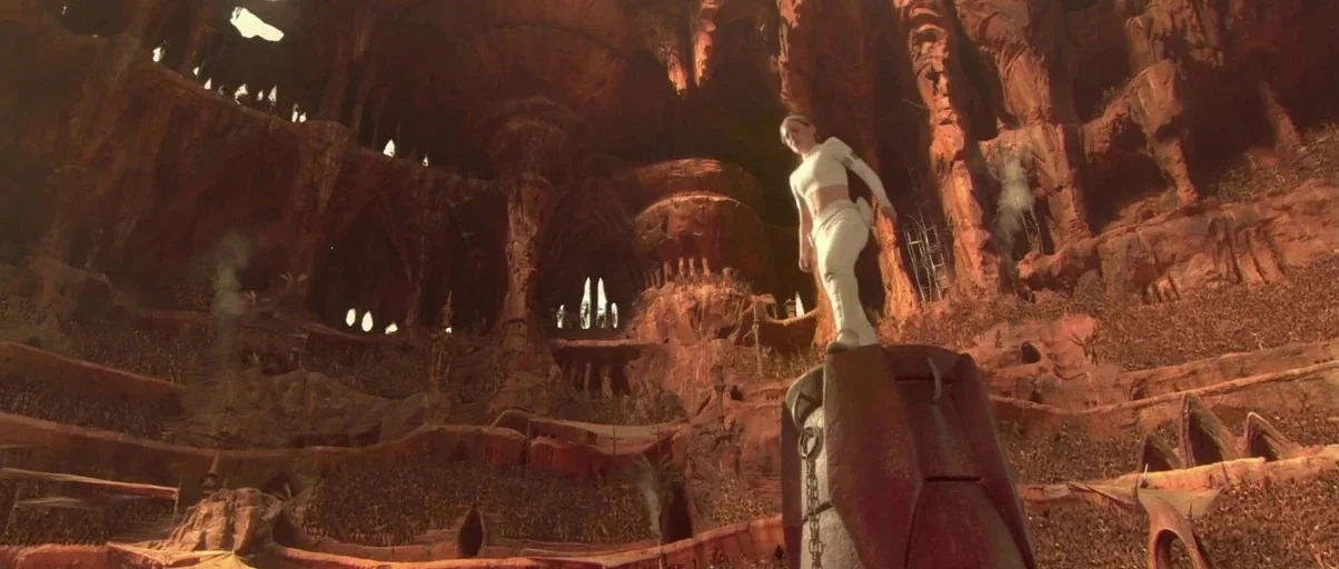 Star Wars: Episode II – Attack of the Clones (2002) movie still: wide — A vast, multi-level sandstone amphitheater carved into rock, filled with…