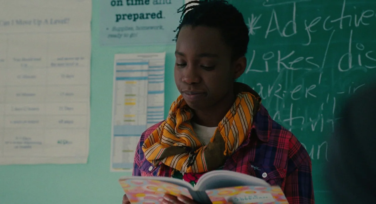 Pariah (2011) movie still: medium — A classroom with a chalkboard featuring written lesson notes and educational posters on walls. A young black…