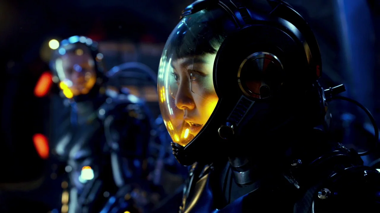 Pacific Rim (2013) movie still: closeup — A dark spaceship interior features two figures in high-tech helmets. The primary subject looks forward…