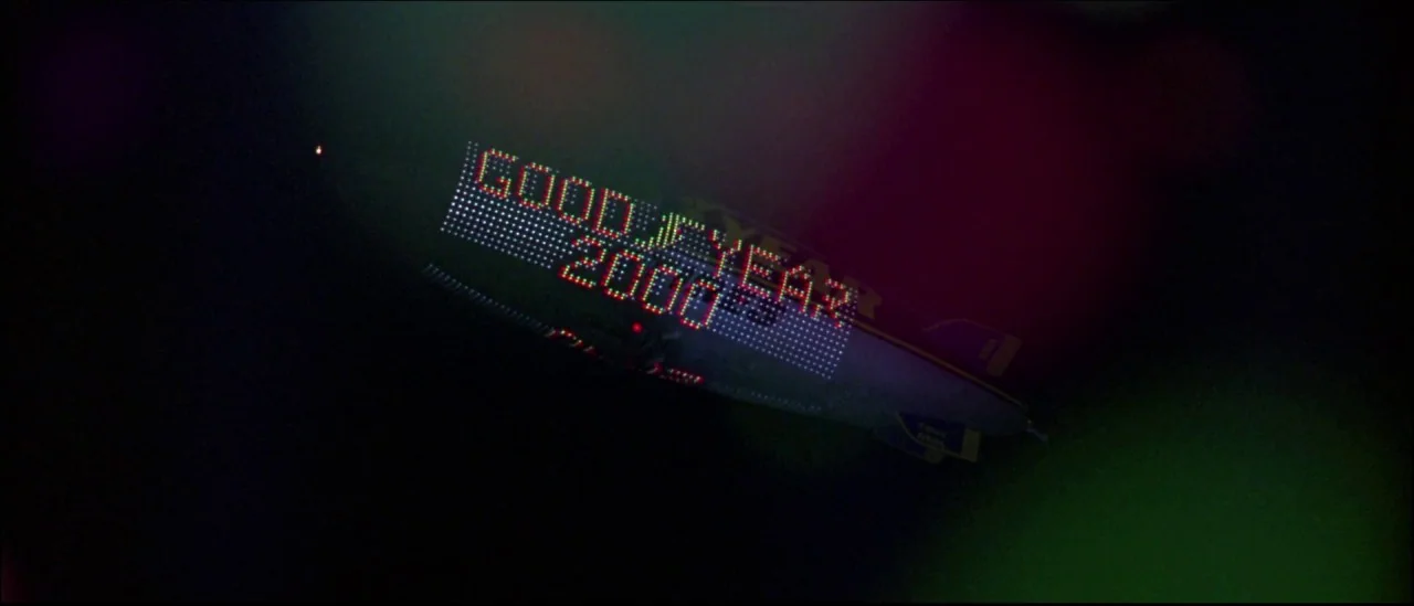Strange Days (1995) movie still: wide — A Goodyear blimp flies through a dark night sky displaying a digital sign. The sign consists of bright red…