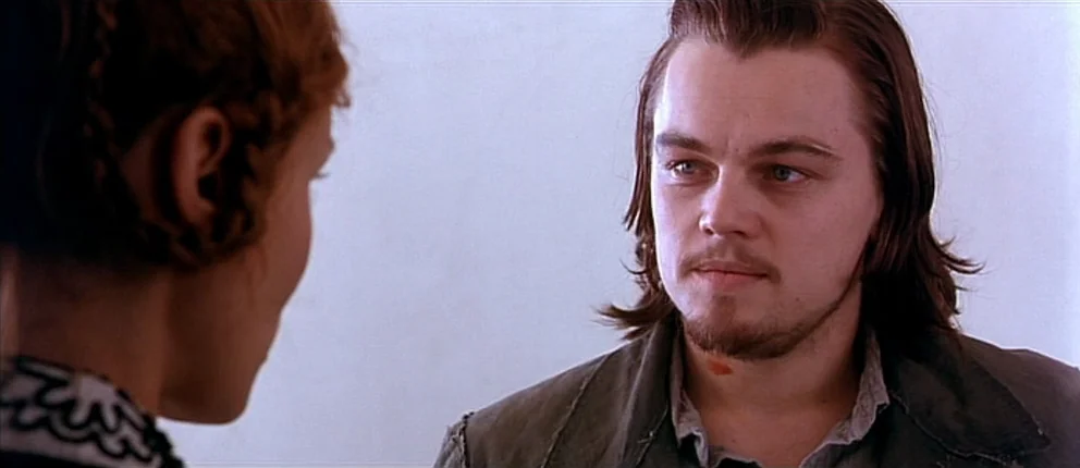 Gangs of New York (2002) movie still: medium — A man and woman face each other against a plain, off-white wall. The man has a small red mark on his…
