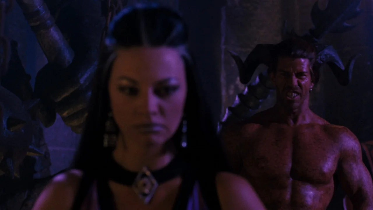 Mortal Kombat: Annihilation (1997) movie still: medium — A dark stone chamber contains a woman and a large muscular horned man. The man stands close…
