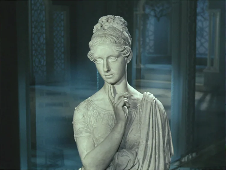 All These Women (1964) movie still: medium — A stone statue of a woman stands in a dimly lit, blue-tinted interior corridor. The figure has her hand…